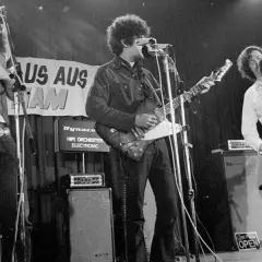 Band auf der Bühne, Gitarrist mit Afro, Sänger mit Schnurrbart, 70er Jahre Rock.