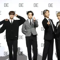 Sechs junge Männer, die wie eine Boyband aussehen, posieren vor einer Wand mit dem Schriftzug "BE".