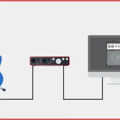 Eine blaue E-Gitarre ist mit einem Audio-Interface verbunden, das wiederum mit einem Computer verbunden ist, der einen Gitarrenverstärker simuliert. So funktioniert eine E-Gitarre digital.