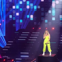 Eine Sängerin steht auf einer Bühne, umgeben von blauen Lichtstrahlen und einem LED-Bildschirm, der "Das große Schlager-Jubiläum" zeigt. Sie ist eine der vielen Schlagerstars Deutschlands.