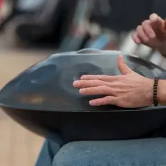 Mann spielt auf einem Hang, einem der ausgefallenen Blasinstrumente, das wie eine UFO-förmige Trommel aussieht.