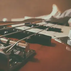 Nahaufnahme eines E-Basses, der sich vom E-Gitarre durch dickere Saiten und einen tieferen Klang unterscheidet.