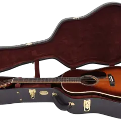Eine wunderschöne Akustikgitarre mit einem warmen Farbverlauf liegt sicher in ihrem dunkelroten, samtbezogenen Koffer. Die bund gitarre ist bereit für ihren nächsten Auftritt.