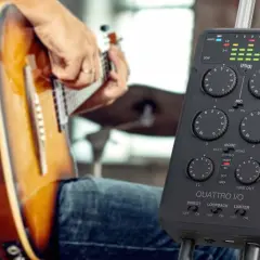 Musiker spielt Gitarre, während ein iRig Quattro I/O bereitsteht, um die Musik aufzunehmen.
