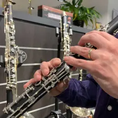Hände üben das Klarinette spielen. Mehrere Klarinetten stehen im Hintergrund.