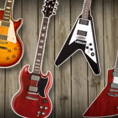 Vier ikonische Gibson Gitarren Modelle: eine Les Paul, SG, Flying V und Explorer, auf Holz Hintergrund.