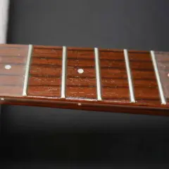 Nahaufnahme des Griffbretts einer Ukulele mit Bundstäbchen und Saiten. Perfekt für Anleitungen zum Ukulele Saiten wechseln.
