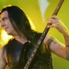 Bassist mit langen Haaren spielt auf einer E-Gitarre, die Hände auf dem Griffbrett. Er ist Teil der lauteste band der welt.