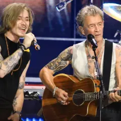 Zwei rock musiker auf der bühne, einer singt ins mikrofon, der andere spielt gitarre.
