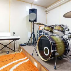 Ein Schlagzeug mit einem großen Bass-Instrument, Keyboard, Mikrofon und Lautsprecher in einem Aufnahmestudio.