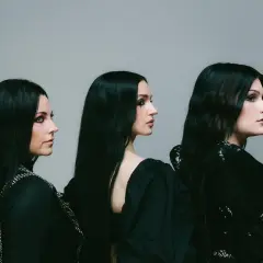 Drei Frauen mit langen schwarzen Haaren und dunklem Make-up, die wie eine Metal-Band posieren.