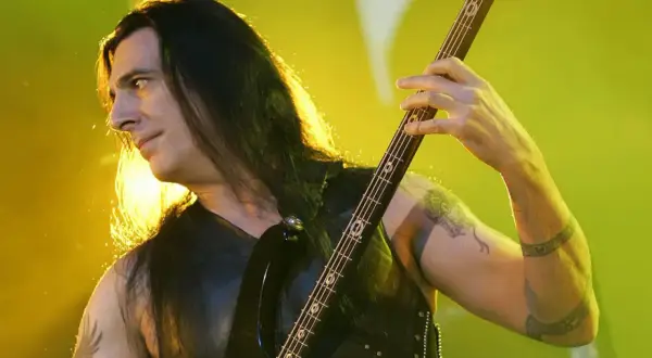 Bassist mit langen Haaren spielt auf einer E-Gitarre, die Hände auf dem Griffbrett. Er ist Teil der lauteste band der welt.