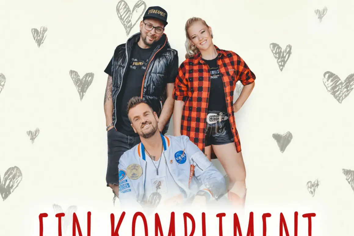 Ein Mann und zwei Frauen, eine girls group, posieren lächelnd vor einem Hintergrund mit Herzen.