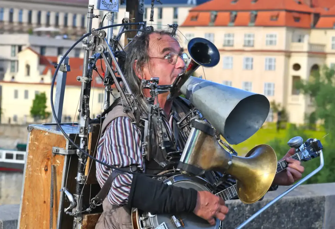 Ein Mann spielt auf einem selbstgebauten Blechblas-Instrument, das mit einem Banjo und vielen mechanischen Teilen verbunden ist.
