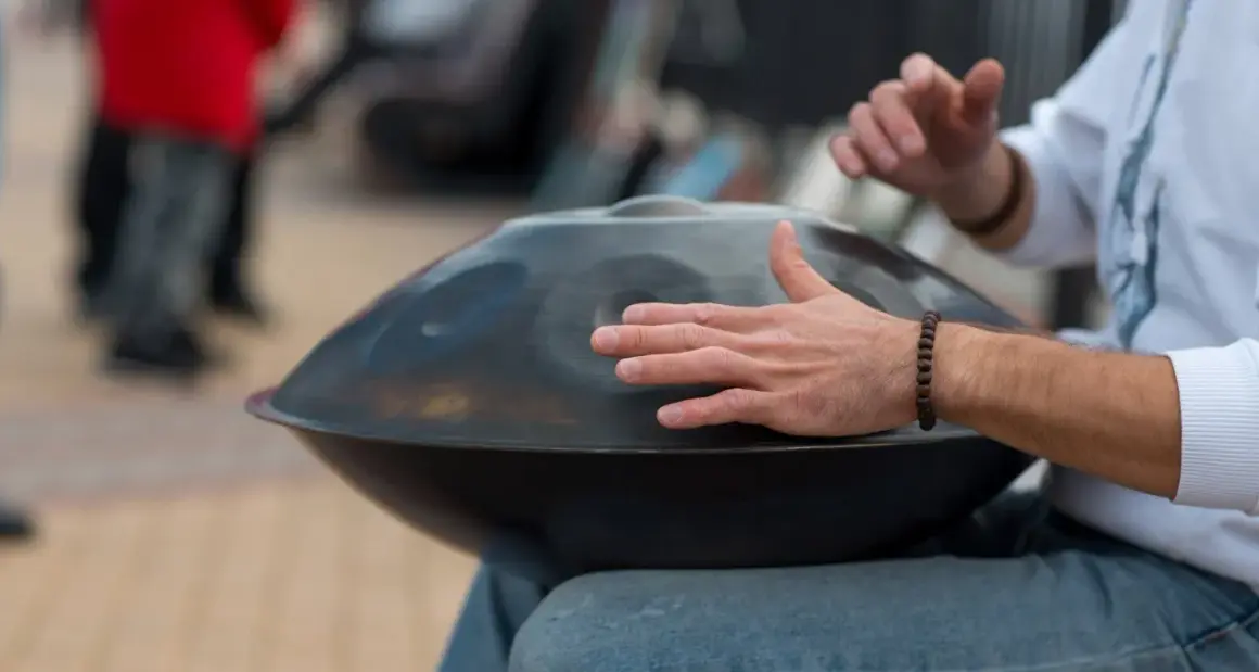 Mann spielt auf einem Hang, einem der ausgefallenen Blasinstrumente, das wie eine UFO-förmige Trommel aussieht.