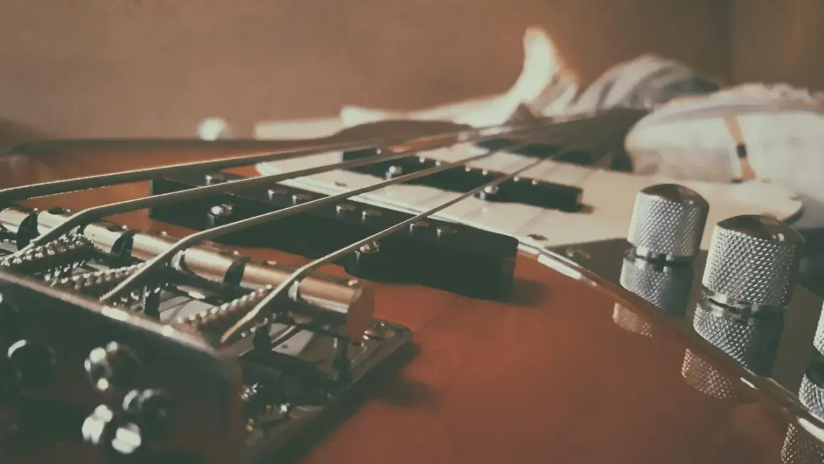 Nahaufnahme eines E-Basses, der sich vom E-Gitarre durch dickere Saiten und einen tieferen Klang unterscheidet.