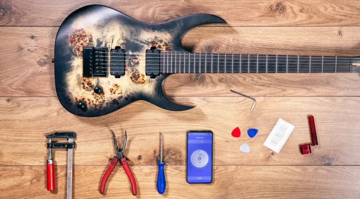 Gitarre mit Werkzeug und Handy-App zur Einstellung des Saitenabstands.
