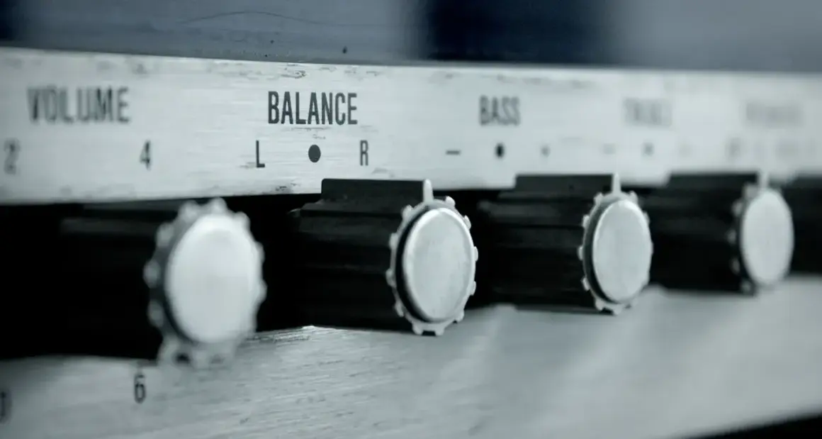 Nahaufnahme von Reglern eines Verstärkers: VOLUME, BALANCE, BASS. Ein Drehknopf für den gain regler ist gut sichtbar.