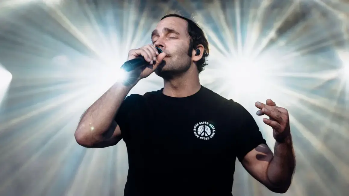 Sänger mit geschlossenen Augen und Mikrofon, der seinen erfolgreichsten Song aller Zeiten performt.