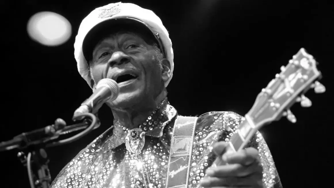 Chuck Berry, ein verstorbener Rockmusiker, singt ins Mikrofon und spielt Gitarre.
