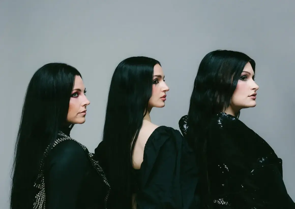 Drei Frauen mit langen schwarzen Haaren und dunklem Make-up, die wie eine Metal-Band posieren.