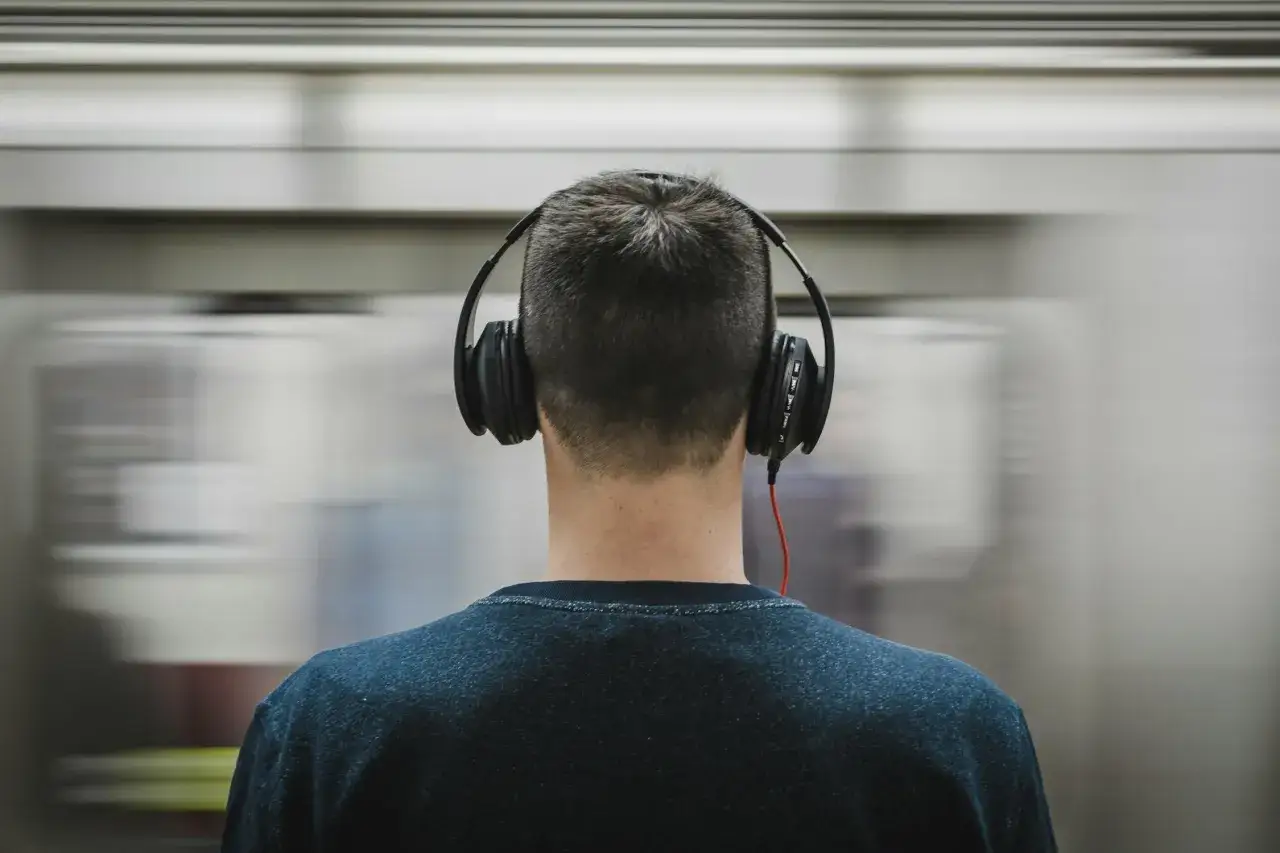 Mann mit Kopfh&ouml;rern h&ouml;rt gruselige Musik, w&auml;hrend ein Zug vorbeirast.
