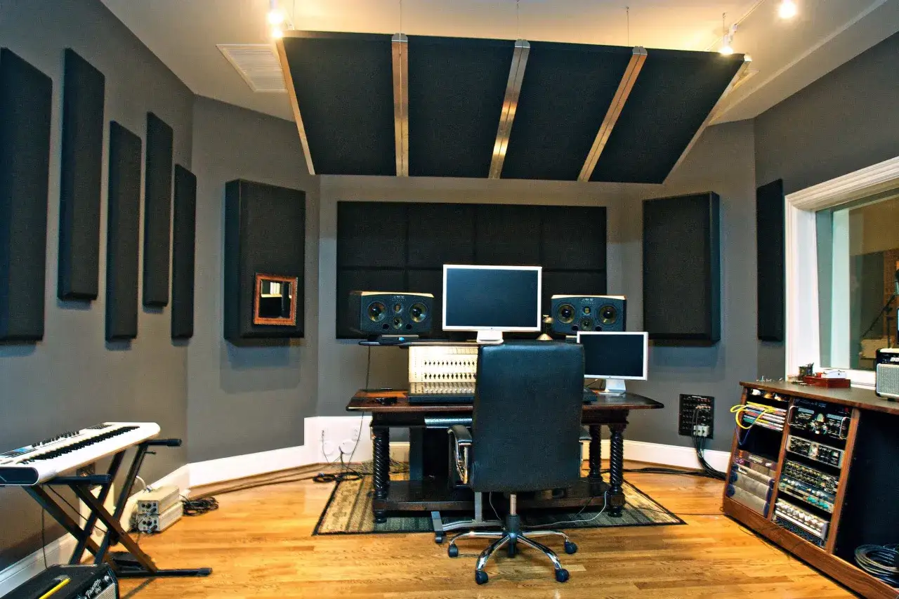 Professionelles home studio akustik mit Schallabsorbern an Wänden und Decke, Mischpult, Monitoren und Keyboard.