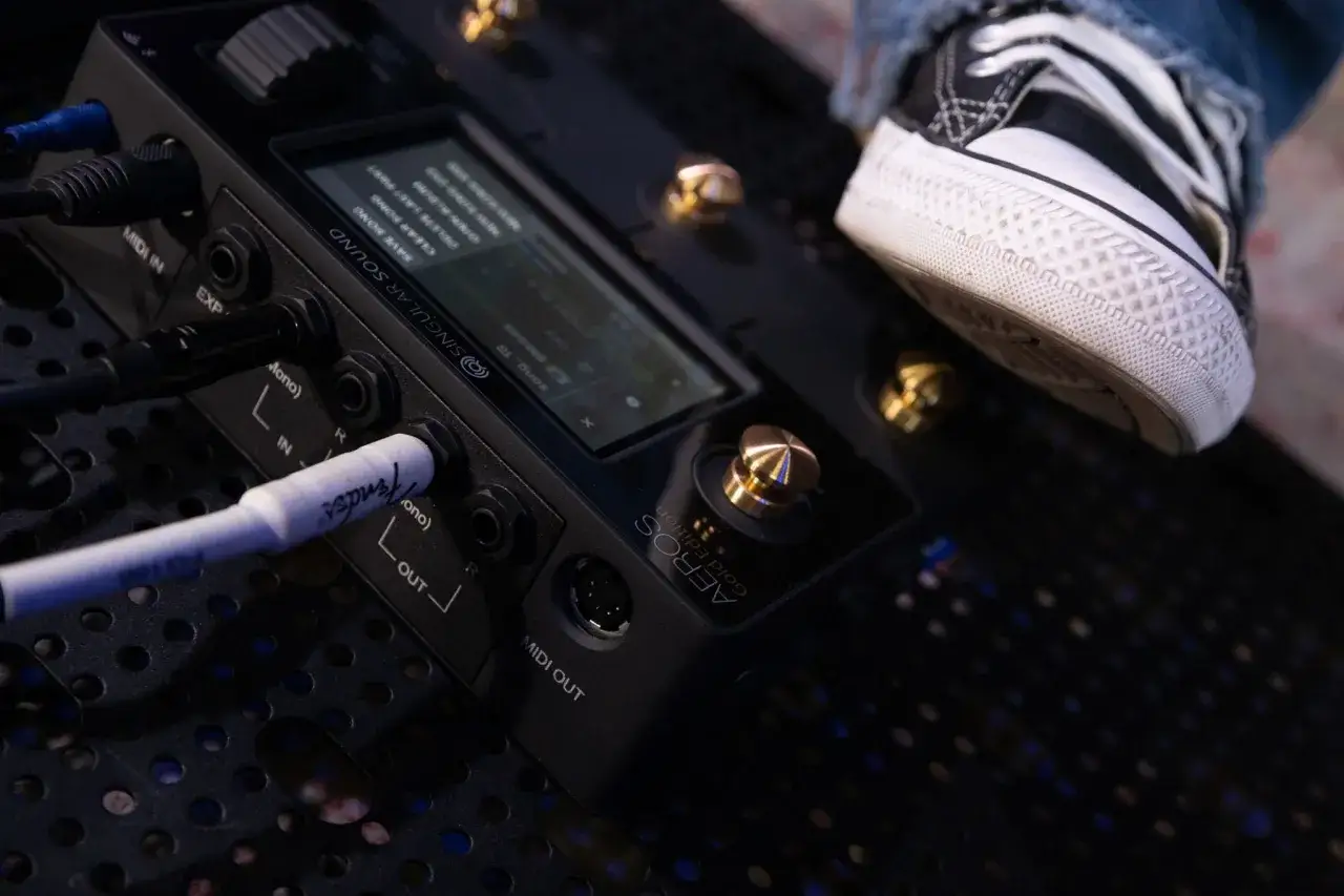 Ein Fuß auf einem Converse-Schuh tritt auf ein Pedal, das mit einem Musik-Looper verbunden ist.
