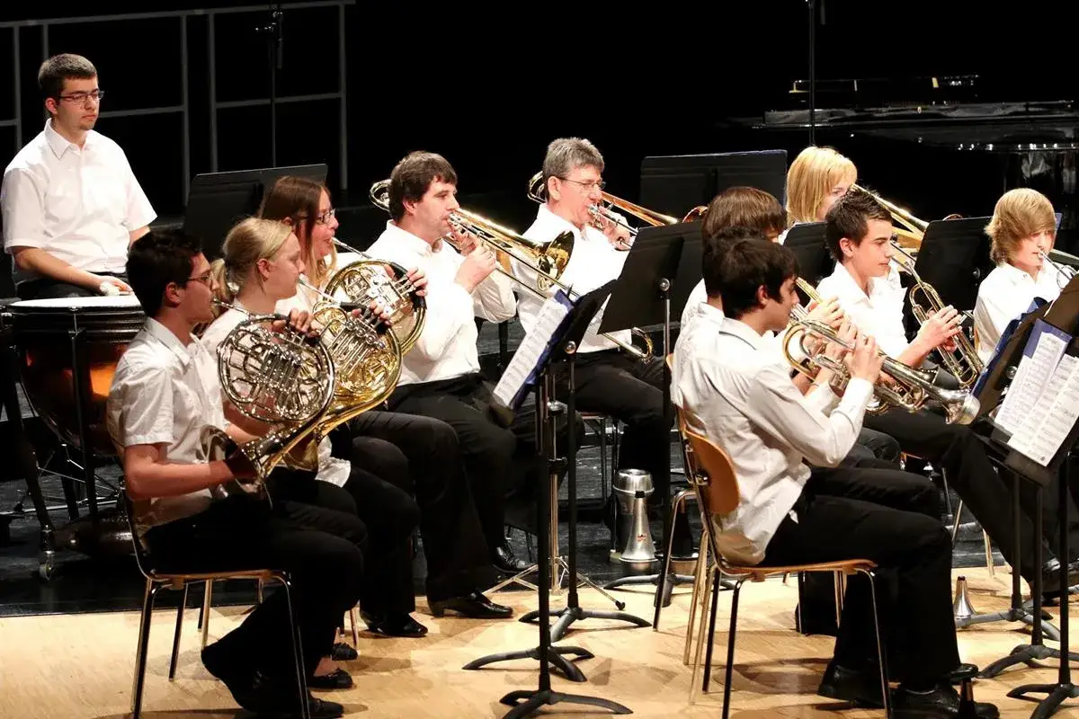 Jugendliche spielen auf verschiedenen Blechblasinstrumenten wie Hörnern und Trompeten.