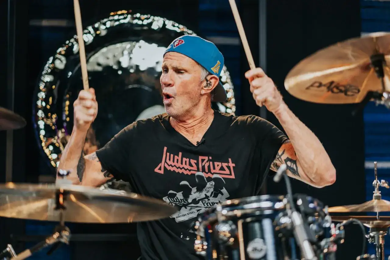 Chad Smith von den Red Hot Chili Peppers spielt ein bekanntes Lied mit Trommeln, sein T-Shirt zeigt Judas Priest.
