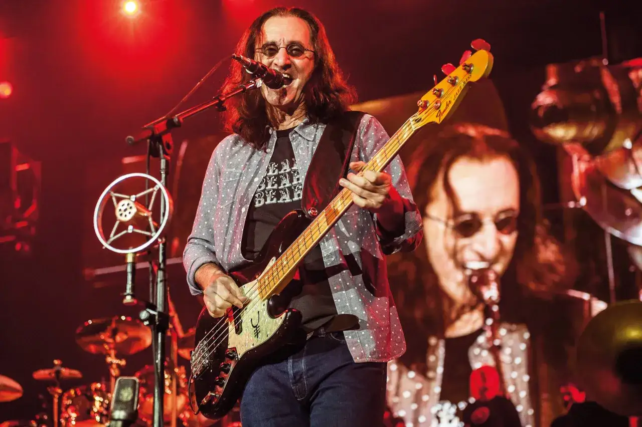 Geddy Lee, der beste Bassist der Welt, spielt auf der Bühne mit seinem Bass. Rotes Licht beleuchtet die Szene.