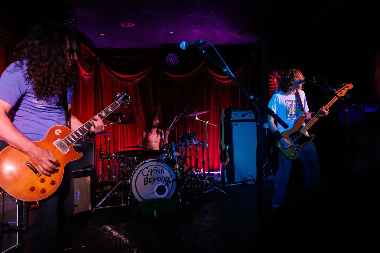 Band spielt rock klassiker auf der Bühne. Gitarrist, Bassist und Schlagzeuger in Aktion.