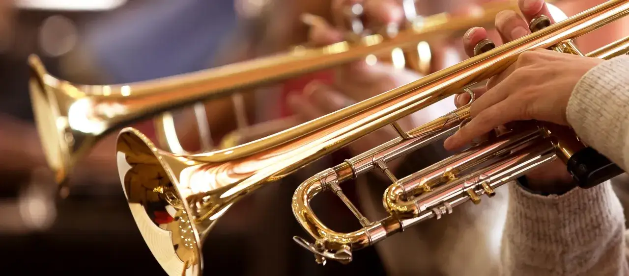 Hände spielen Trompeten. Das glänzende Messinginstrument, ein typisches Brass-Instrument, erzeugt Melodien.