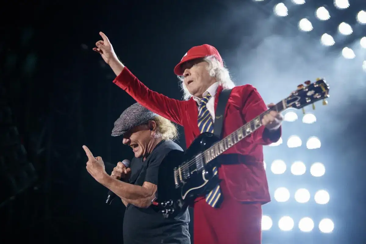 Angus Young und Brian Johnson von AC/DC rocken die Bühne mit bekannten Liedern. Angus spielt Gitarre, Brian singt ins Mikrofon.