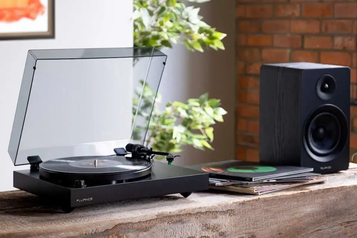 Schwarzer Plattenspieler mit Vinyl-Platten und Lautsprecher auf einem Holztisch. Ein stilvolles Vinyl-Setup f&uuml;r Musikliebhaber.
