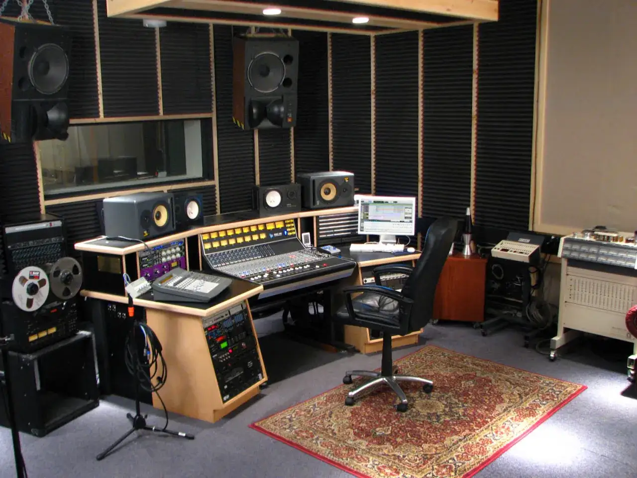 Professionelles studio setup mit Mischpult, Monitoren, Computer und Aufnahmegeräten.