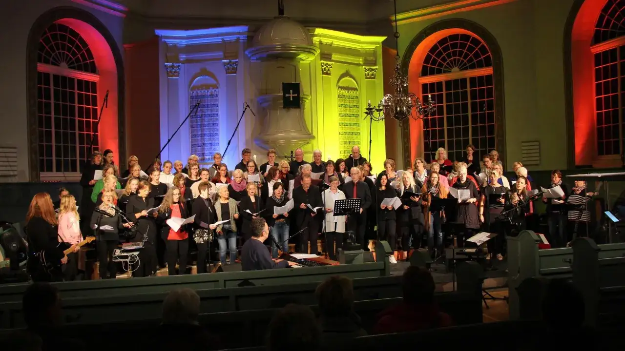 Ein Chor singt bekannte Gospel Songs in einer Kirche, beleuchtet von bunten Lichtern.