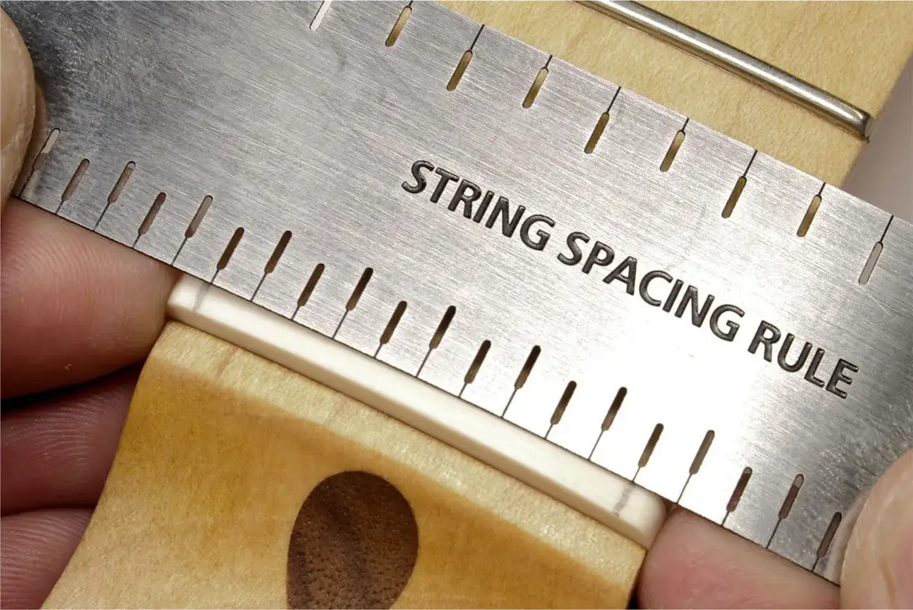 Pr&auml;zise Einstellung des Saitenabstands an einer Gitarre mit einer speziellen Messlehre.