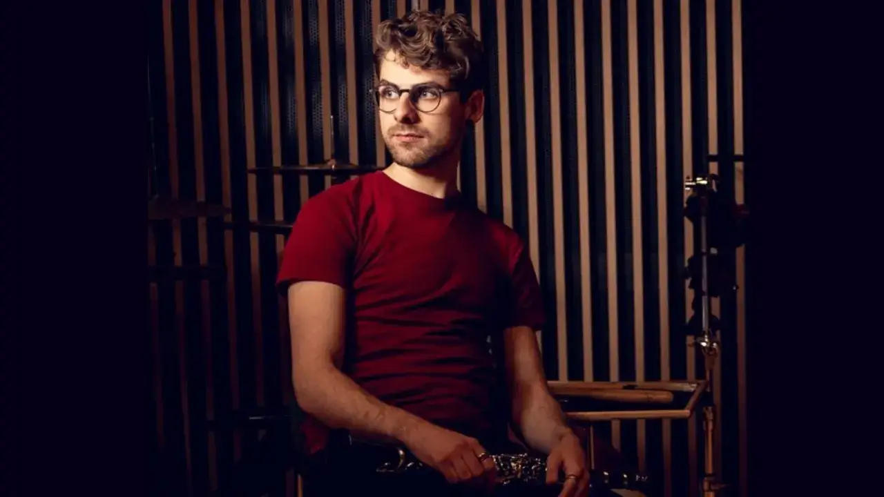 Ein Mann mit Brille und rotem T-Shirt sitzt und hält eine Klarinette. Die Klarinette Stimmung ist perfekt für den Auftritt.