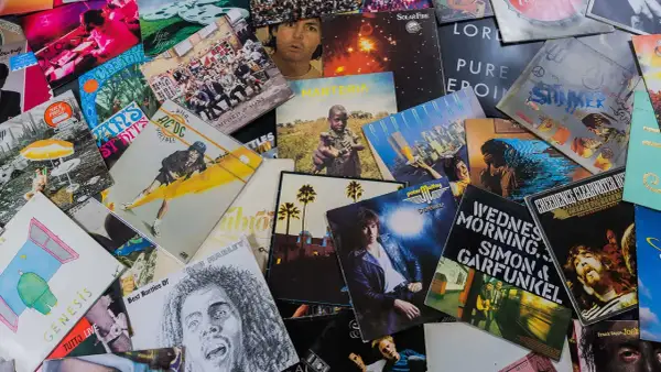 Bunte Schallplatten zeigen, welche Musikrichtungen es gibt: Rock von AC/DC, Pop von Genesis, Reggae von Bob Marley und mehr.