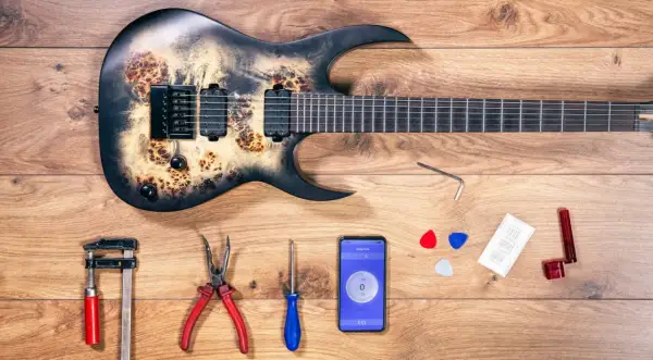 Gitarre mit Werkzeug und Handy-App zur Einstellung des Saitenabstands.