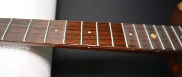 Nahaufnahme des Griffbretts einer Ukulele mit Bundstäbchen und Saiten. Perfekt für Anleitungen zum Ukulele Saiten wechseln.