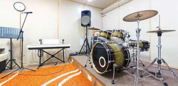 Ein Schlagzeug mit einem großen Bass-Instrument, Keyboard, Mikrofon und Lautsprecher in einem Aufnahmestudio.